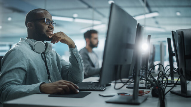 Authentic Office: Motivated Black IT Programmer Working on Desktop Computer. Male Website, Software Engineer Developing App, Program, Video Game. Terminal with Coding Language. - Powered by Adobe