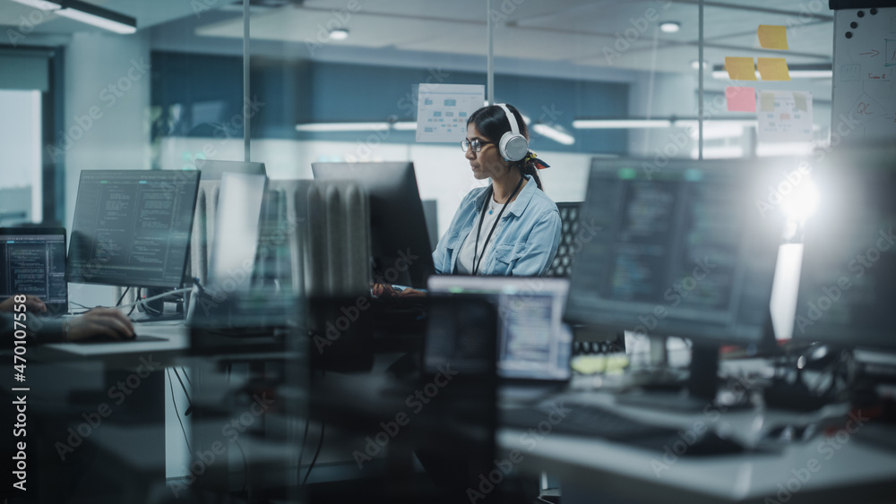 Poster Diverse Office: Indian IT Programmer Working on Computer. Female Specialist Creating Innovative Software. Engineer Developing App, Program, Video Game. Wearing Headphones Listening Podcast, Music