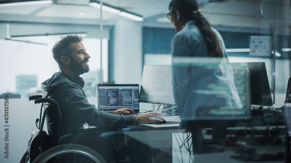 Fototapete Disability-Friendly Office: Brilliant IT Programmer with Disability in a Wheelchair Talks with Colleague while Working on Computer. Software Engineers Develop Innovative App, Program.