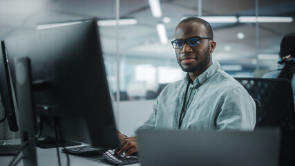 Real Office: Professional Black IT Programmer Working on Desktop Computer. Male Website Developer and Software Engineer Developing App, Video Game. Progressive, Innovative and Inspirational Person