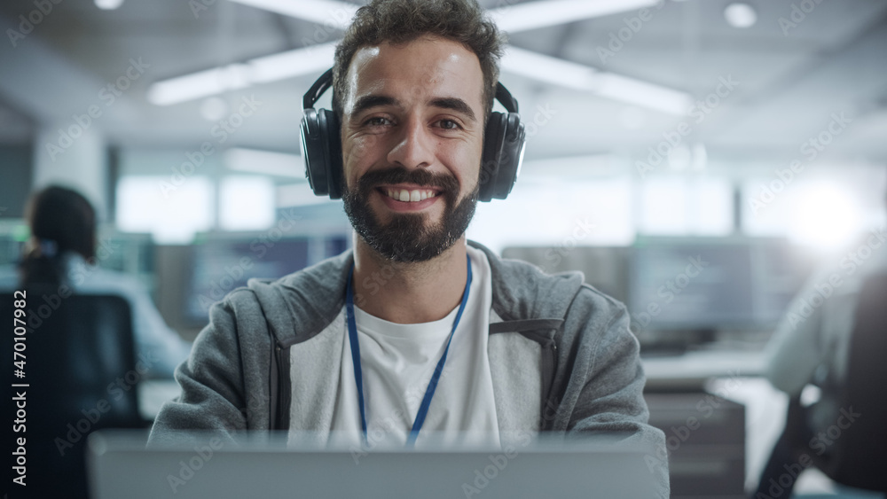 Poster Office: Portrait of Happy IT Programmer Wearing Headphones Working on Desktop Computer, Looking at Camera and Smiling. Male Software Engineer Developing App, Video Game. Listening to Podcast, Music