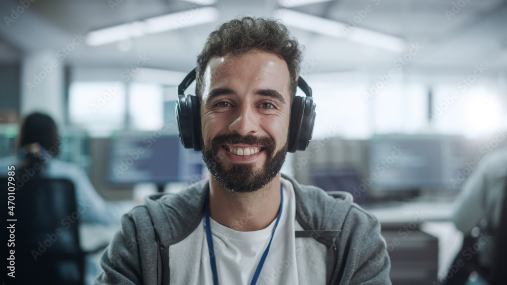 Poster Office: Portrait of Happy IT Programmer Wearing Headphones Working on Desktop Computer, Looking at Camera and Smiling. Male Software Engineer Developing App, Video Game. Listening to Podcast, Music