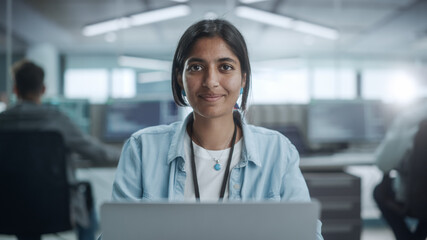 Diverse Office: Portrait of Beautiful Indian IT Programmer Working on Desktop Computer, Smiling and Looking at Camera Kindly. Female Software Engineer Creating Innovative App, Program, Video Game