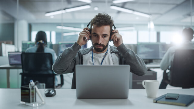 Office: Portrait of Smiling IT Programmer Put on Headphones, Work on Desktop Computer. Male Website Developer, Software Engineer Developing App, Video Game. Listening to Podcast, Music.