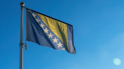 Bosnia Herzegovina national flag waving in the wind on a deep blue sky. Diplomacy and international...