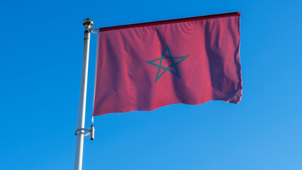 National flag of Morocco on a flagpole in front of blue sky. Diplomacy concept. International relations.