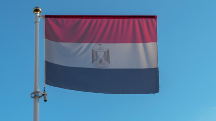 National flag of Egypt on a flagpole in front of blue sky with sun rays and lens flare. Diplomacy concept.