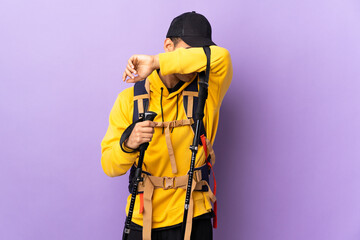 African American man with backpack and trekking poles over isolated background covering eyes by hands