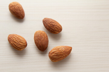 淡い木目の上に置かれたいくつかのアーモンドのアップ