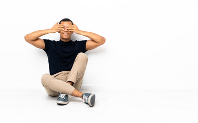 African American man sitting on the floor covering eyes by hands