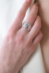 Trending silver ring with pearls on a beautiful young girl in a white fashionable jacket. Beauty and fashion 