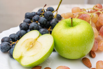 Set of ripe and juicy fruits and berries, green apple, white and black grapes and almonds for a healthy diet