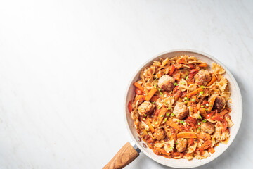 One pan dish. Pasta with onion, red pepper, garlic, tomatoes, carrot and meatballs. White background copy space. Text space.