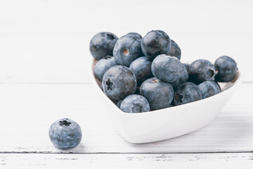 Blueberries in a plate of hearts on a white background. Fresh ripe blue berries. Love food concept. Top view, flat lay, copy space.