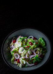 Mediterranean red beans salad with mix of lettuce leaves and onion on black bowl