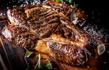 Grilled Ribeye Steak on bones on wooden board, prime cowboy steak on dark background