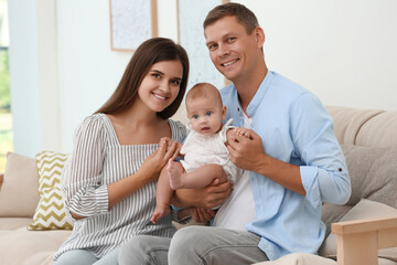 Portrait of happy family with their cute baby at home