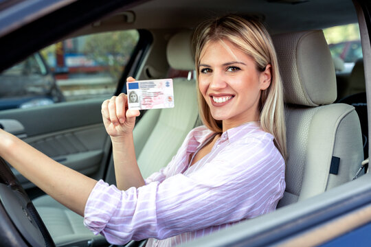Young attractive woman holding her driving license