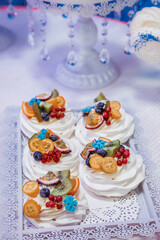cupcakes with white cream, garnished with berries and fruits, on a white tray with lace edges