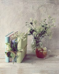 Jasmine tea, stack of books with fresh wildflowers bookmarks on wooden table, learning concept, alternative medicine, romantic