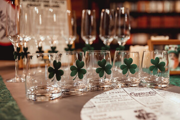glasses with Irish clover on the table against the background of cutlery and glasses