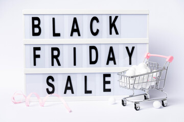 Promotion composition Black friday sale text on lightbox with trolley isolated on white background.