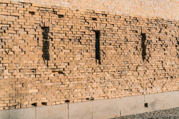 Gun loopholes in the old wall of the fortification. Bullet. Facade. Embrasure. Loophole. Battlement. Destructions