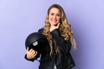 Fototapeta na wymiar Young Brazilian woman holding a motorcycle helmet isolated on purple background happy and smiling