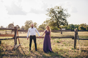 Couple on a date. Purple dress. Bride and groom. Walk in the field. Love story.