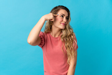 Young Brazilian woman isolated on blue background making the gesture of madness putting finger on the head