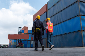 Industrial worker works with co-worker at overseas shipping container yard . Logistics supply chain management and international goods export concept .