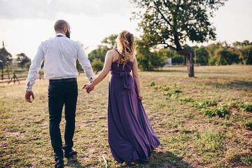 Couple on a date. Purple dress. Bride and groom. Walk in the field. Love story.