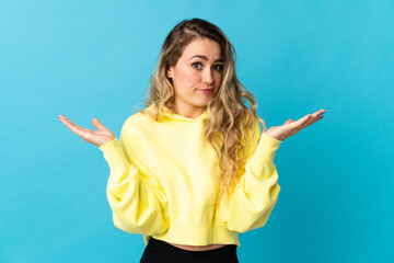 Young Brazilian woman isolated on blue background having doubts while raising hands