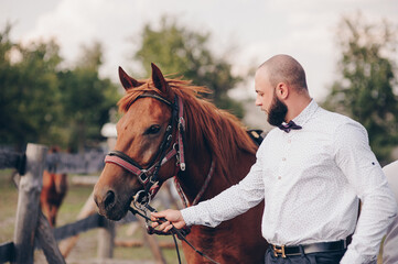The groom in a white shirt and a purple bow tie. Horse riding.