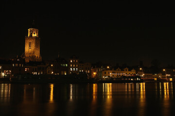 Fototapeta na wymiar The Great Church and buildings in the City of Deventer, the Netherlands, at night with reflection in the water 