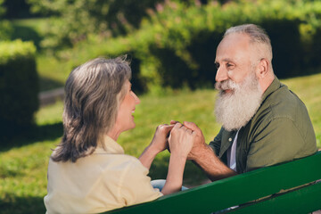 Fototapeta premium Photo of happy positive old retired people woman man sit bench hold hands nature green outdoors in urban park
