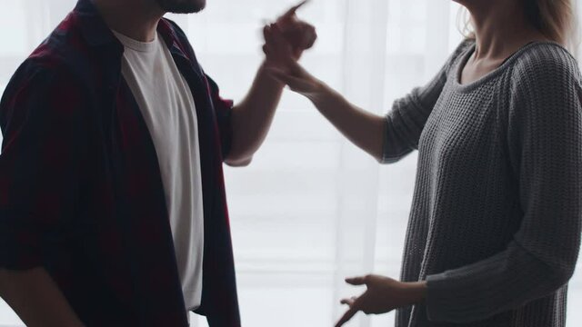 Couple family divorce. Husband and wife are disputing at home and emotionally gesticulating with hands, side view. Married couple swears in living room expressively gesticulate with hands