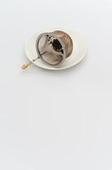 metal tea strainer with tea leaves on a white stoneware plate