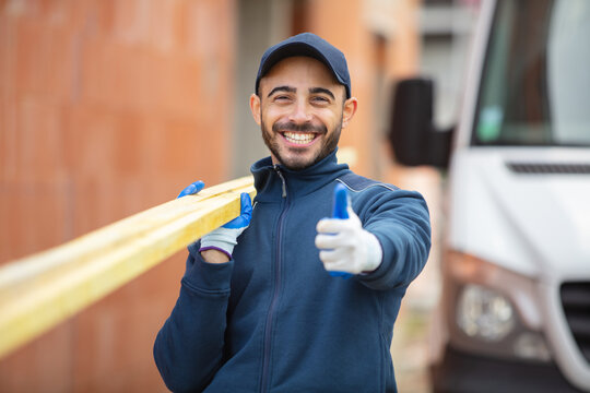 young manual worker carrying wooden planks