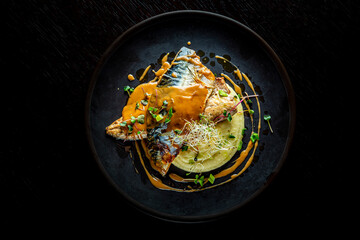 Fillet of mackerel with mashed potatoes and celery on dark background