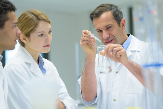 smiling scientist teacher holding dna model in laboratory