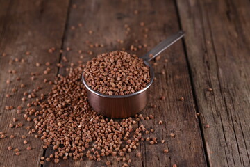 Buckwheat in a measuring glass on a wooden background