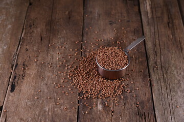 Buckwheat in a measuring glass on a wooden background