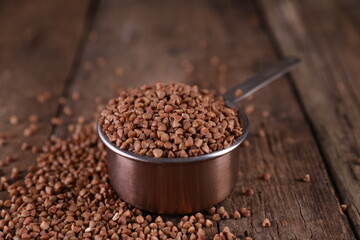 Buckwheat in a measuring glass on a wooden background
