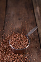 Buckwheat in a measuring glass on a wooden background