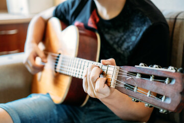 Guitar lessons for beginners. Close up of hands playing guitar. Online Guitar Lessons, enjoying favorite hobby, leisure. Acoustic guitars for beginners.