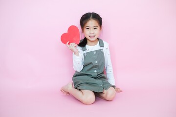 Obraz na płótnie Canvas Portrait beautiful cute asia child girl on pink background with red heart sign, valentine day in love concept