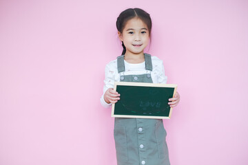 Portrait beautiful cute asian child girl on pink background with drawing board holding in hand