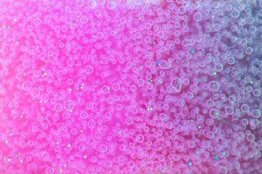 Small clear air bubbles floats in pink and purple fluid.