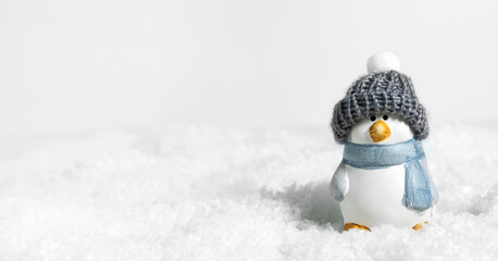 Christmas white snow background, panorama. Happy cute penguin in a winter hat on snowdrifts with...